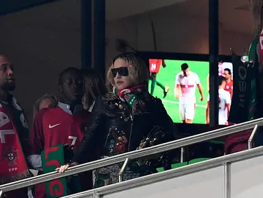 Penyanyi AS, Madonna (tengah) bersama anaknya David Banda menyaksikan pertandingan kualifikasi Piala Dunia 2018 antara Portugal dan Swiss di Stadion Luz di Lisbon (10/10). Madonna tampil mengenakan jaket dan kacamata hitam. (AFP Photo/Francisco Leong)