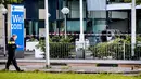 Seorang polisi berjalan dekat sebuah mobil van yang menabrak pintu depan gedung tempat surat kabar ternama Belanda, De Telegraaf di Amsterdam, Selasa (26/6). Akibatnya mobil van itu terbakar dan menyebakan kerusakan pada gedung. (KOEN VAN WEEL/ANP/AFP)