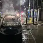 Petugas pemadam kebakaran memadamkan api yang membakar mobil Ford di jalan depan Pos Polisi Masjid Cut Meutia, Jakarta Pusat, Rabu (2/7/2024) malam. (Liputan6.com/Raden Trimutia Hatta)