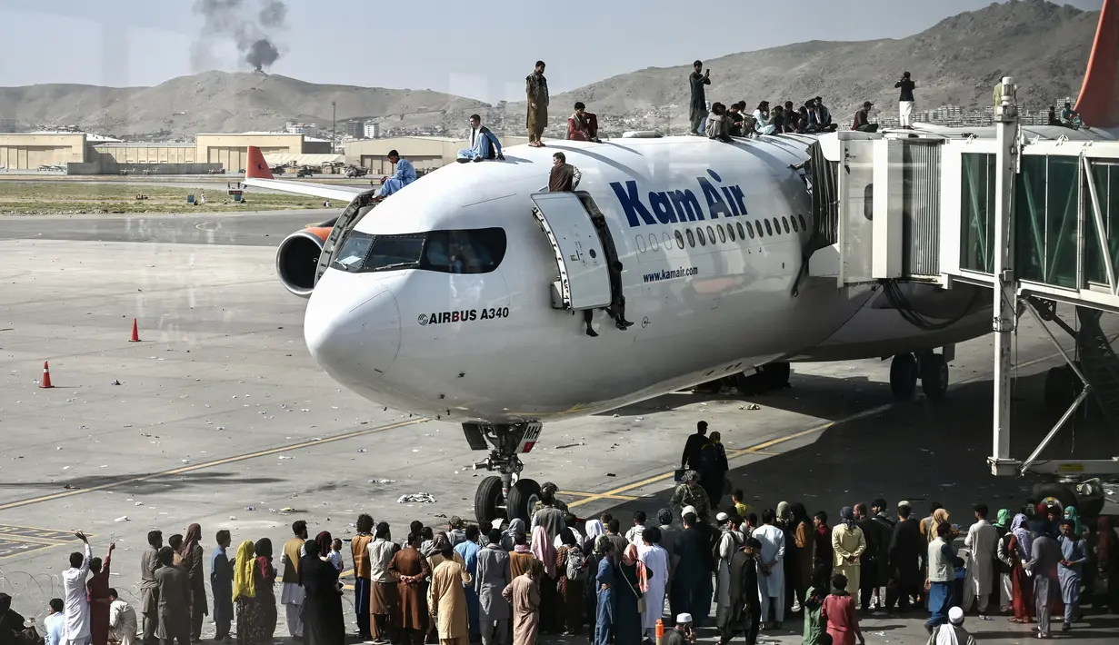 Orang-orang Afghanistan naik ke atas sebuah pesawat saat mereka menunggu di bandara Kabul (16/8/2021). Bandara internasional di Kabul dilanda kekacauan dan kemacetan lalu lintas yang parah. (AFP/Wakil Kohsar)