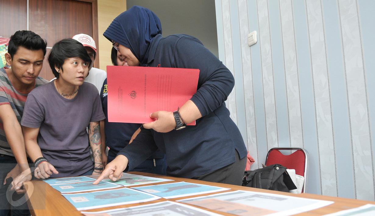 Petugas DVI Polri menunjukan ke pihak keluarga foto properti hasil postmortem sekunder dari jenazah Korban KM Zahro di RS Polri, Jakarta, Selasa (3/1). (Liputan6.com/Yoppy Renato)