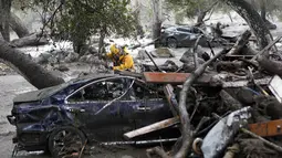 Seorang anggota tim Long Beach Search and Rescue mencari korban selamat terjangan longsor di sebuah mobil di Montecito, California, Selasa, (9/1). Sejumlah rumah warga hanyut tersapu longsor. (AP Photo/Daniel Dreifuss)