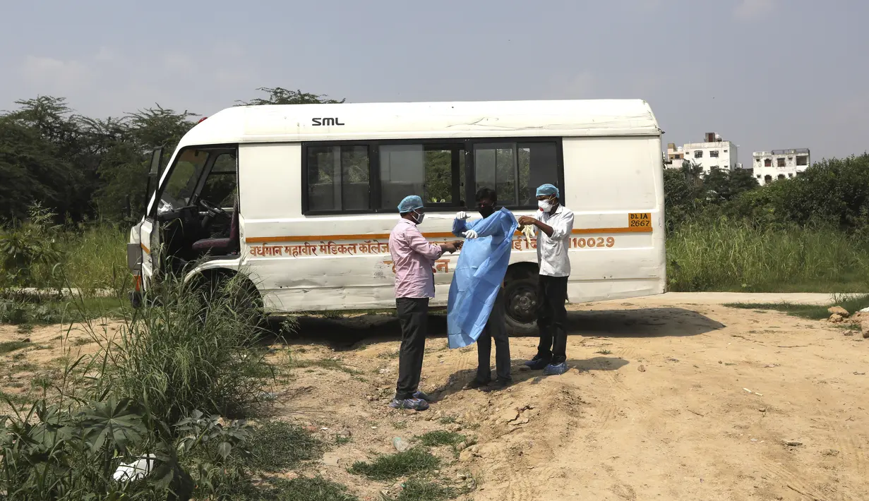 Petugas kesehatan membantu seorang pria mengenakan  pakaian pelindung diri saat akan menguburkan putranya yang meninggal akibat COVID-19 di New Delhi (16/9/2020). Otoritas India melaporkan bahwa total kasus virus Corona (COVID-19) di wilayahnya telah melampaui 5 juta.  (AP Photo/Manish Swarup)