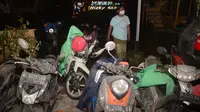 Seorang warga berjalan melewati sepeda motor para pengungsi yang diselimuti abu vulkanik pasca erupsi Gunung Semeru di desa Sumberurip, Lumajang (4/12/2021). Wakil Bupati Lumajang Indah Masdar melaporkan ada satu orang yang meninggal dunia akibat erupsi Gunung Semeru. (AFP/Juni Kriswanto)