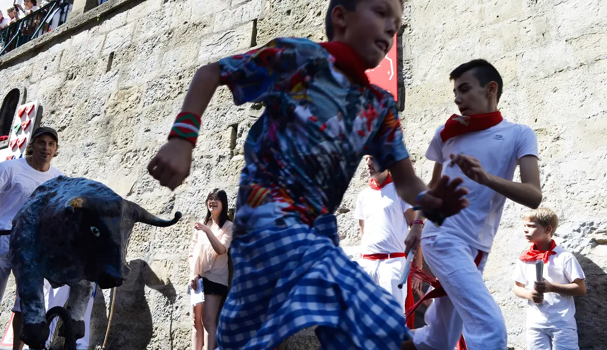 Anak-anak berlarian saat mengikuti Encierro Txiki selama Festival San Fermin di Pamplona, Spanyol (13/7). Encierro Txiki  atau Small Bull Run ini adalah bagian dari Festival San Fermin yang khusus untuk anak-anak. (AFP Photo/Ander Gillenea)