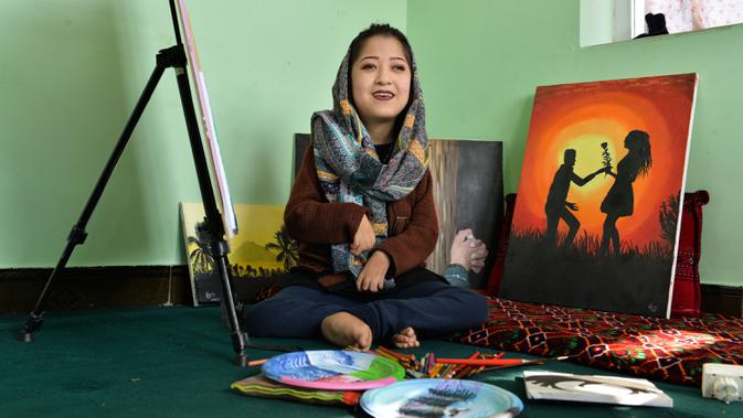 Seniman Robaba Mohammadi duduk di sebelah lukisannya selama wawancara dengan AFP mulut di studionya di Kabul pada 5 Desember 2019. Melalui lukisan, seniman asal Afghanistan ini mengekspresikan bahwa wanita dan disabilitas bukan lagi hal yang bisa dipandang sebelah mata. (NOORULLAH SHIRZADA/AFP)
