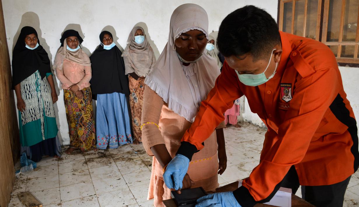 Pengungsi Rohingya mengantre untuk diambil sidik jari untuk menjalani prosedur identifikasi oleh petugas kepolisian di pusat penampungan sementara bekas kantor Imigrasi Punteuet, Aceh Utara (26/6/2020). Mereka menjalani identifikasi dan pemeriksaan tes Covid-19. (AFP Photo/CHAIDEER MAHYUDDIN)