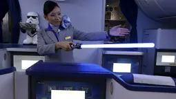 Seorang Pramugari menyapa pengunjung sambil memegang lightsabre atau pedang laser di pesawat Boeing 787 Dreamliner, Singapura, Kamis (12/11/2015).  Pesawat bertema Star Wars ini menjadi pertama di Asia Tenggara. (REUTERS/Edgar Su)
