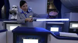 Seorang Pramugari menyapa pengunjung sambil memegang lightsabre atau pedang laser di pesawat Boeing 787 Dreamliner, Singapura, Kamis (12/11/2015).  Pesawat bertema Star Wars ini menjadi pertama di Asia Tenggara. (REUTERS/Edgar Su)