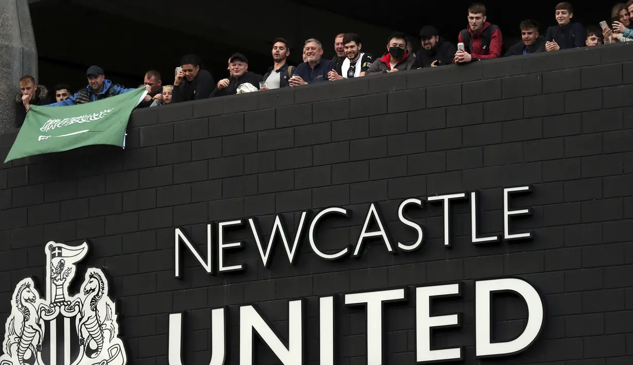 Pendukung Newcastle United membawa bendera Arab Saudi saat merayakan di luar St. James'Park di Newcastle Upon Tyne, Inggris (7/10/20210). Newcastle mengumumkan pembelian klub oleh Public Investment Fund (PIF), Kamis (7/10/2021) malam WIB. (AP Photo / Scott Heppell)