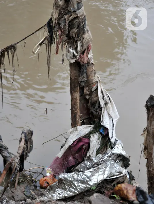 Kondisi tanggul kayu yang rusak dan penuh sampah di bantaran Kali Ciliwung, Rawajati, Pancoran, Jakarta, Minggu (5/1/2020). Tanggul dari kayu dolken dan karung pasir yang baru dibangun pada akhir Desember 2019 itu rusak hingga dipenuhi sampah akibat terjangan arus banjir. (merdeka.com/Iqbal Nugroho)