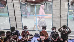 Anak-anak mendengarkan dongeng yang dikisahkan petugas di tenda pengungsian di SDN 09 Kebon Kosong, Kemayoran, Jakarta, Selasa (31/8/2021). Kegiatan bertujuan menghilangkan trauma atau rasa takut serta kebosanan anak-anak korban kebakaran saat berada di pengungsian. (merdeka.com/Iqbal S. Nugroho)
