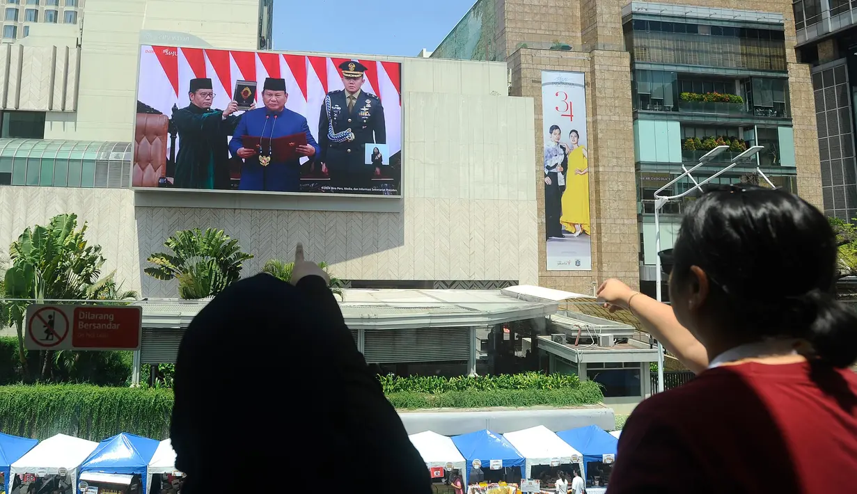Warga menyaksikan prosesi pelantikan Presiden dan Wakil Presiden terpilih 2024-2029, Prabowo Subianto-Gibran Rakabuming Raka dari layar videotron di kawasan Bundaran Hotel Indonesia, Jakarta, Minggu (20/10/2024). (merdeka.com/Arie Basuki)
