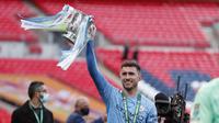 Bek Manchester City, Aymeric Laporte mengangkat trofi saat merayakan kemenangan atas Tottenham Hotspur pada pertandingan final Piala Liga Inggris di stadion Wembley di London, Senin (26/4/2021). (AP Photo/Alastair Grant)