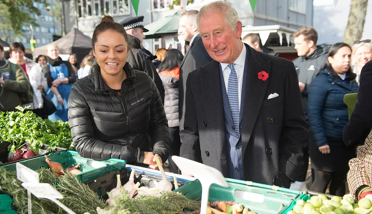 Pangeran Charles berbincang dengan pedagang ketika mengunjungi Swiss Cottage Farmers Market di London utara, Rabu (6/11/2019). Kunjungan Pangeran Charles dan Camila untuk mengucapkan selamat dan memperingati ulang tahun ke-20 pasar tersebut. (Eddie Mulholland / POOL / AFP)