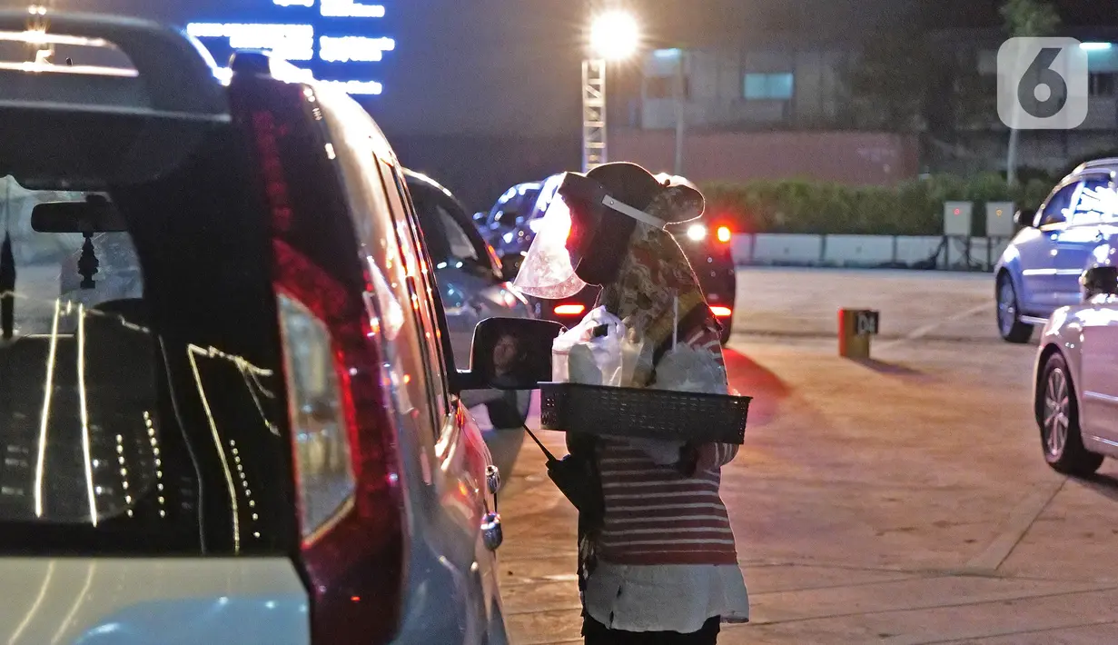 Pegawai membawa pesanan makanan penonton yang menyaksikan pemutaran film secara drive-in di Cikarang, Bekasi, Jawa Barat, Rabu (3/6/2020). Jelang new normal, pengelola pusat hiburan menghadirkan konsep gaya hidup dengan standar protokol kesehatan. (Liputan6.com/Herman Zakharia)