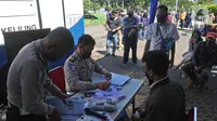 Petugas polisi melayani warga yang mengurus Surat Izin Mengemudi (SIM) di mobil layanan SIM Keliling Masjid At-Tin Jakarta, Kamis (4/6/2020). Direktorat Lalu Lintas Polda Metro Jaya mengoperasikan kembali layanan mobil SIM Keliling untuk mengantisipasi antrean pemohon. (Liputan6.com/Herman Zakharia)