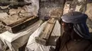 Pekerja Mesir berdiri dekat mumi wanita bernama Thuya dalam sarkofagus yang baru dibuka di Kota Luxor, Sabtu (24/11). Mumi itu diawetkan dengan baik di dalam sarkofagus yang belum pernah dibuka sejak lebih dari 3.000 tahun lalu. (Khaled DESOUKI/AFP)