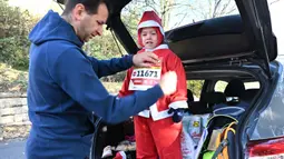 Seorang anak dengan kostum Sinterklas sebelum mengikuti lomba lari tradisional menyambut Natal di Budapest, Hungaria, pada 3 Desember 2023. (ATTILA KISBENEDEK/AFP)