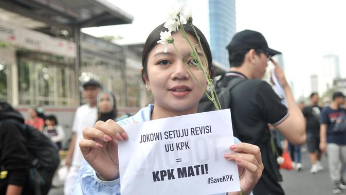 Warga berpose dengan bunga yang diberikan dalam Aksi Selamatkan KPK di hari bebas kendaraan bermotor kawasan Bundaran HI, Jakarta, Minggu (8/9/2019). (merdeka.com/Iqbal S. Nugroho)