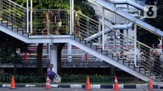 Warga bersandar di salah satu tiang JPO di kawasan Jalan HR Rasuna Said, Jakarta, Rabu (8/7/2020). Wabah Covid-19 memengaruhi kondisi kesejahteraan masyarakat dan pertumbuhan ekonomi Indonesia pada tahun 2020 yang diproyeksikan -0,4 sampai dengan 1,0 persen. (Liputan6.com/Helmi Fithriansyah)