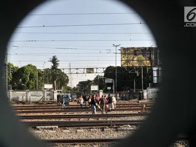 Warga menyeberangi perlintasan rel kereta api di kawasan Pisangan Baru, Jakarta, Selasa (10/9/2019). Mereka nekat menantang maut menyeberangi rel di dekat stasiun Jatinegara tersebut lantaran tidak adanya akses jembatan penyeberangan orang (JPO). (merdeka.com/Iqbal Nugroho)