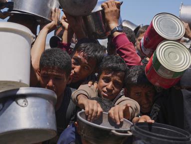 Warga Palestina berebut untuk mendapat pembagian makanan di sebuah dapur umum, Khan Younis, Jalur Gaza selatan, Senin 2 Juni 2025. (AP Photo/Abdel Kareem Hana)