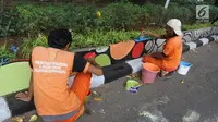 Petugas PPSU Gondangdia mengecat pembatas jalan dengan warna-warni Asian Games di kawasan Menteng, Jakarta, Kamis (12/7). Cat lukisan dinding beraneka gambar dan bentuk untuk menyambut HUT kemerdekaan RI dan Asian Games 2018. (Liputan6.com/Arya Manggala)