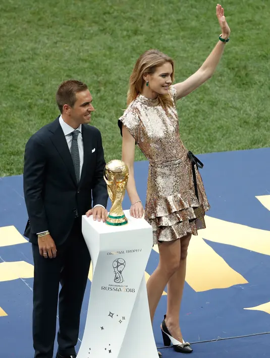 Mantan kapten Jerman Philipp Lahm (kiri) dan model Rusia Natalia Vodianova (kanan) mempersembahkan trofi Piala Dunia pada penutupan Piala Dunia 2018 Rusia di Stadion Luzhniki, Moskow (15/7). (AFP Photo / Adrian Dennis)