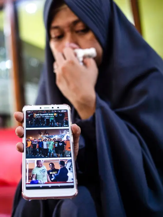 Lyan Kurniawati, istri dari penyelam Syachrul Anto yang meninggal dunia saat melakukan evakuasi jatuhnya pesawat Lion Air PK-LQP, menunjukkan foto-foto sang suami setelah prosesi pemakaman di Surabaya, Jawa Timur, Sabtu (3/11). (JUNI KRISWANTO/AFP)