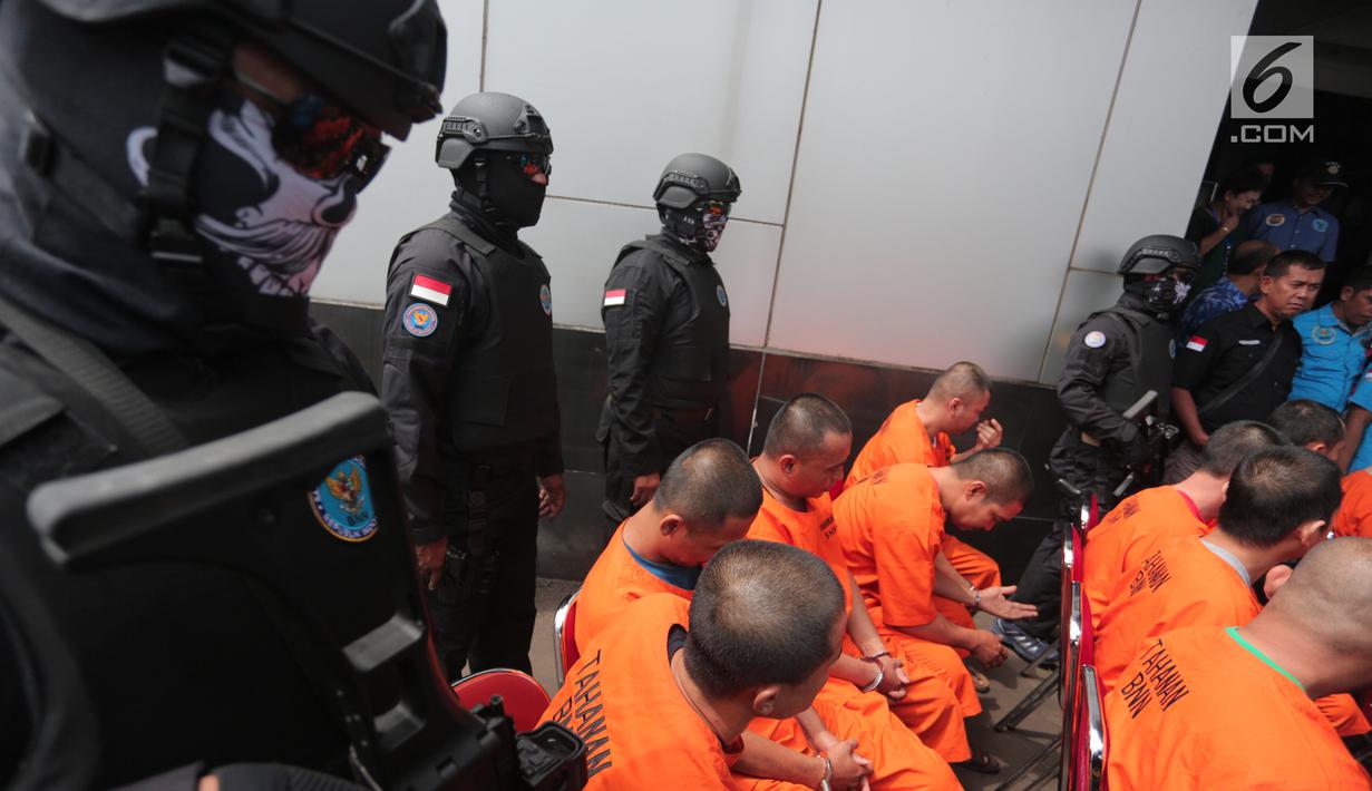 Polisi menjaga tersangka kasus penyelundupan narkoba oleh empat jaringan internasional di Kantor BNN, Jakarta, Selasa (10/10). Selain itu, 14 orang tersangka turut diamankan, tiga diantaranya ditangkap di beberapa lapas.(Liputan6.com/Faizal Fanani)