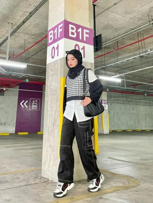 Cargo pants warna hitam dipadu dengan kemeja dan sneaker. Vest motif houndstooth hitam bikin gayamu makin pop up! (Instagram/adivaselsa).