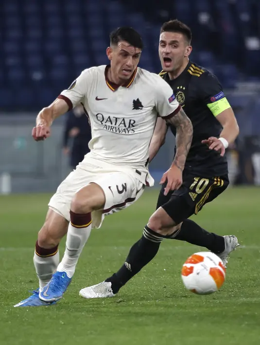 Bek Ajax Amsterdam, Nicolas Tagliafico menendang  bola di depan bek AS Roma, Rick Karsdorp pada leg kedua perempat final Liga Europa di Olimpico, Jumat (16/4/2021) dini hari WIB. AS Roma melaju ke semifinal Liga Europa musim ini setelah bermain imbang 1-1 lawan Ajax. (AP Photo/Alessandra Tarantino)