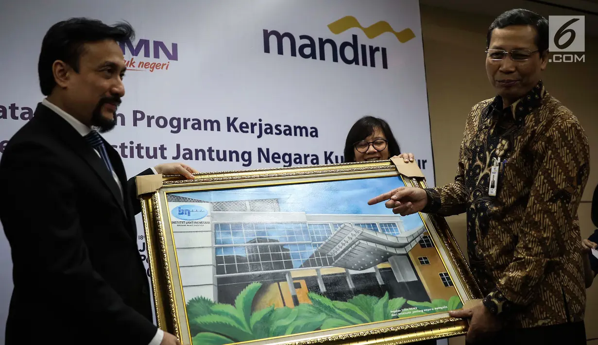 Chief Operating Officer IJN Kuala Lumpur Akmal Arief Mohamed Fauzi memberi lukisan kepada Direktur Retail Banking Bank Mandiri Tardi saat penandatanganan perjanjian kerjasama di Jakarta, Rabu (6/9). (Liputan6.com/Angga Yuniar)