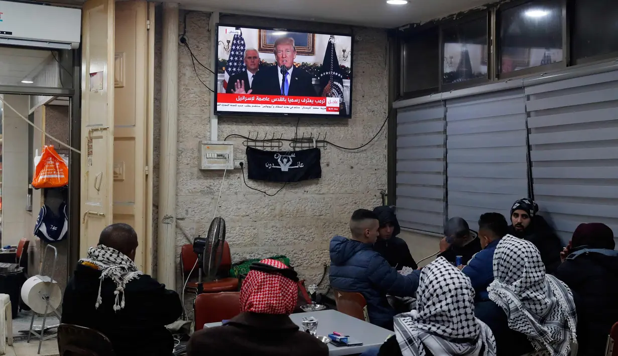 Warga Palestina menonton pidato Presiden AS, Donald Trump di sebuah kafe di Yerusalem (6/12). Donald Trump rencananya juga akan mulai memindahkan kedutaan AS dari Tel Aviv ke Yerusalem. (AFP Photo/Ahmad Gharabli)