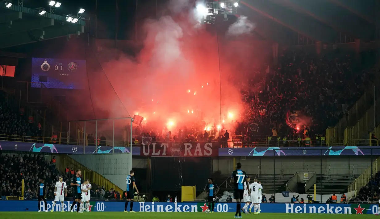 Suporter Paris Saint-Germain (PSG) menyalakan flare saat timnya bertanding menghadapi Club Brugge pada laga Grup A Liga Champions di Stadion Jan Breydel, Bruges, Belgia, Selasa (22/10/2019). PSG menang 5-0. (Kenzo TRIBOUILLARD/AFP)