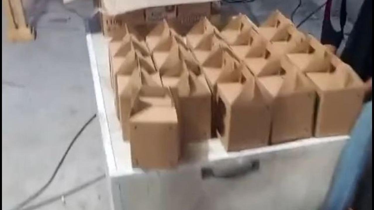 Kemudian ia berjalan ke arah meja tempat menaruh souvenir untuk para tamu. Dari kejauhan, tampak kotak-kotak berwarna cokelat. Jika dilihat dari jauh, kita mungkin mengira jika isi souvenir ini berupa gelas atau benda lain.