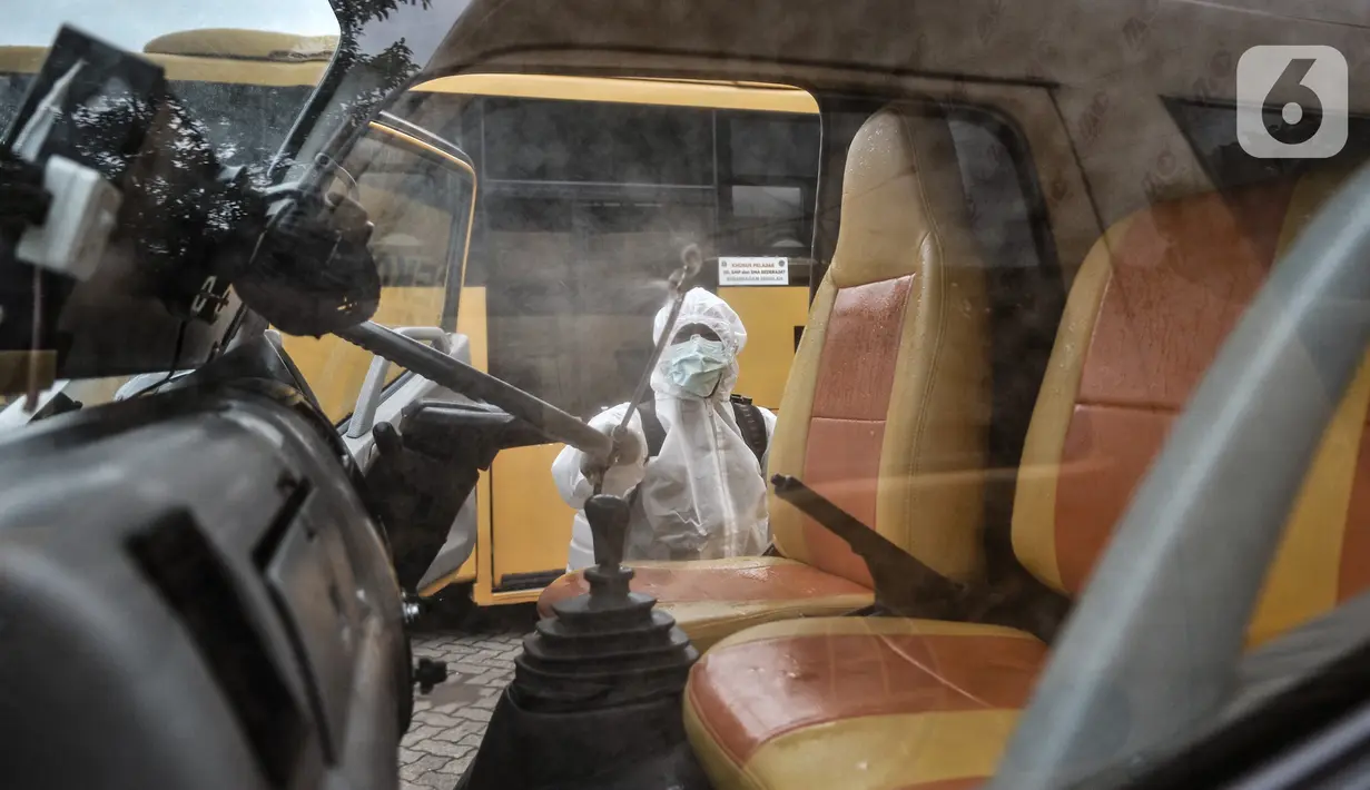 Petugas Kebersihan Bus (PKB) menyemprotkan disinfektan pada bus sekolah di Pool Unit Pelayanan Angkutan Sekolah (UPAS) DKI Jakarta, Kramat Jati, Selasa (5/1/2021). Sterilisasi bus sekolah rutin dilakukan usai digunakan mengangkut pasien terpapar Covid-19 ke RS rujukan. (merdeka.com/Iqbal Nugroho)