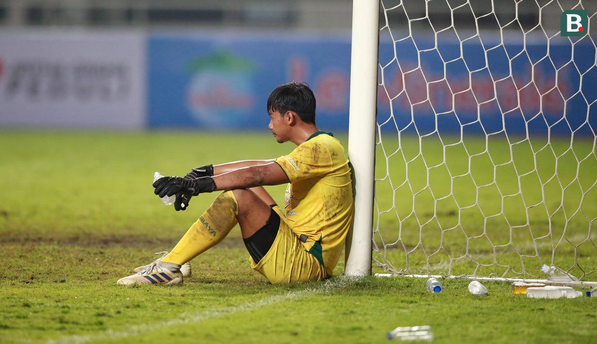 Kiper Persebaya Surabaya, Satria Tama terduduk lesu usai ditaklukkan Persikabo 1973 dalam laga pekan pertama BRI Liga 1 2022/2023 antara Persikabo 1973 melawan Persebaya Surabaya di Stadion Pakansari, Bogor, Senin (25/7/2022) malam WIB. (Bola.com/M Iqbal Ichsan)