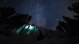 Anggota tim Arnica, Pierre mendaki tebing es saat sesi latihan malam hari di dekat La Lecherette, Hongrin, Kota Vaud, Swiss, Rabu (14/2). Pierre mendaki di bawah malam yang penuh bintang. (Anthony Anex/Keystone via AP)