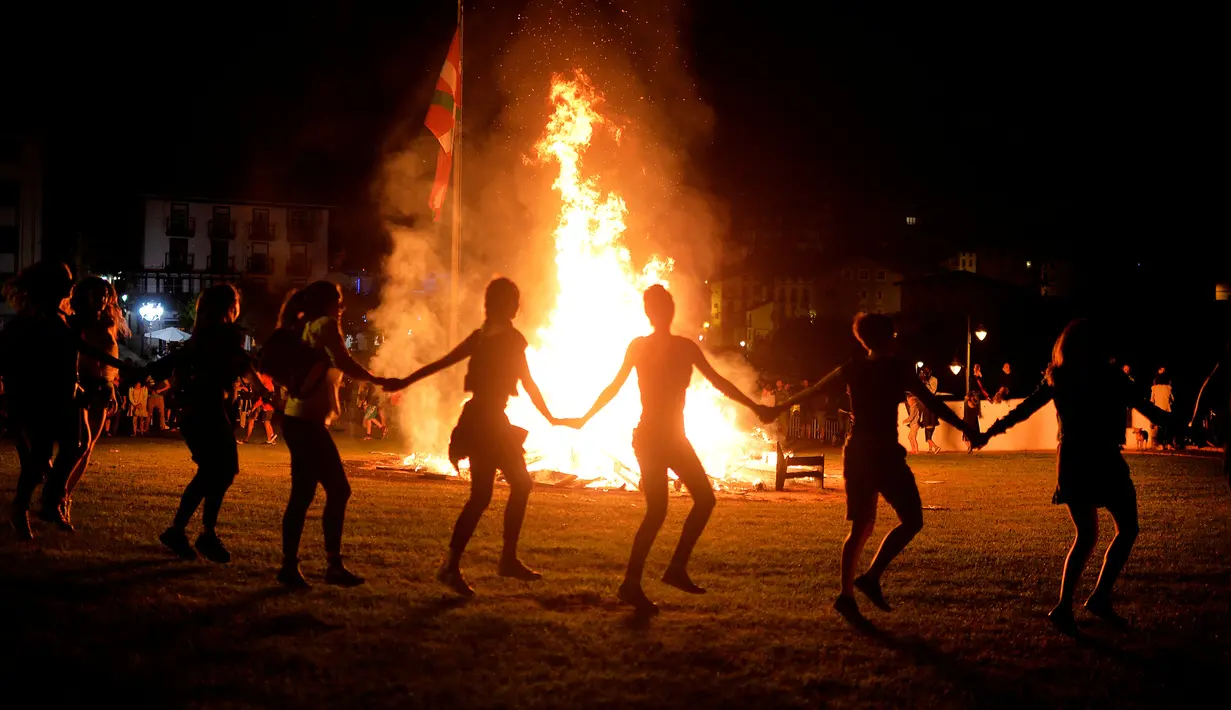 Sejumlah orang mengitari kobaran api saat mengikuti tradisi malam San Juan's (Saint John) di Gijon, Spanyol, (24/6). Malam San Juan juga dilakukan dengan berenang saat musim panas tiba. (REUTERS/Vincent West)