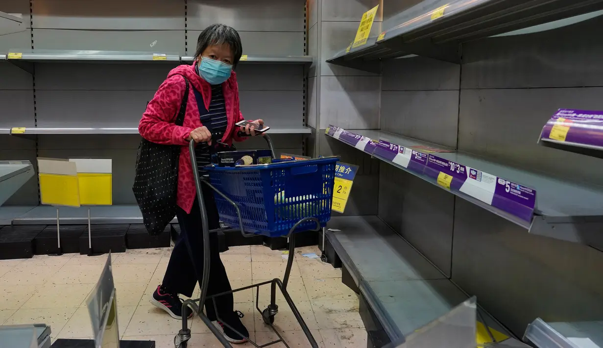 Warga mengenakan masker berjalan melewati rak kertas tisu yang kosong di sebuah supermarket di Hong Kong, Kamis (6/2/2020). Di tengah kelangkaan masker wajah untuk melindungi terhadap wabah virus corona, tisu toilet tiba-tiba juga menjadi salah satu barang yang langka di Hong Kong. (AP/Vincent Yu)