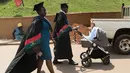 Pasangan wisudawan membawa anak mereka didalam kereta bayi untuk mengikuti upacara wisuda ke-68 di Universitas Makerere di Kampala, Uganda (19/1). (AFP Photo/Michele Sibiloni)