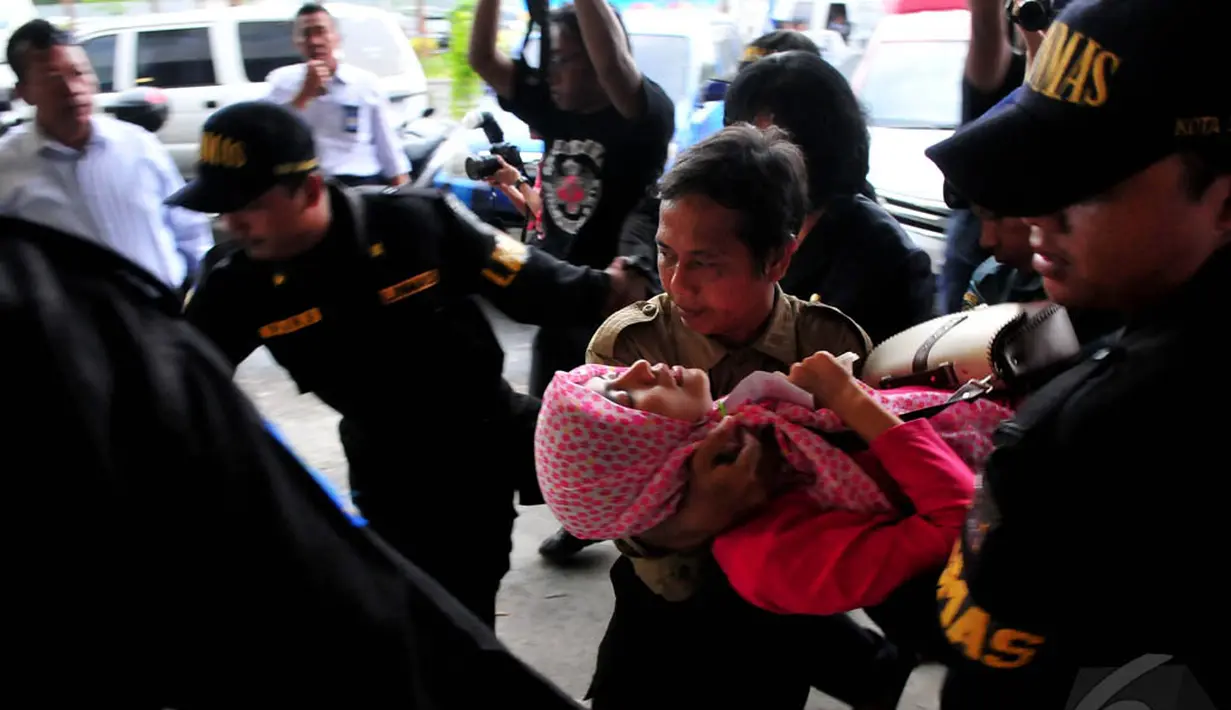 Petugas medis menolong seorang keluarga korban penumpang AirAsia QZ8501 yang pingsan di Bandara Juanda, Surabaya, Selasa (30/12/2014). (Liputan6.com/Johan Tallo)