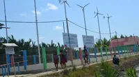 Bocah-bocah Bondan, Ujungalang, Kampung Laut, Cilacap pulang sekolah dan melintas di instalasi energi listrik terbarukan tenaga angin dan matahari. (Foto: Liputan6.com/Muhamad Ridlo).
