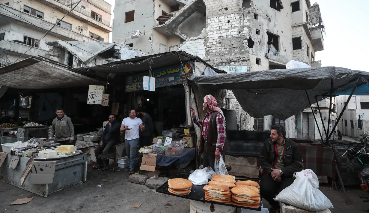 Warga Suriah membeli produk makanan di pasar menjelang buka puasa pada hari kedua bulan suci Ramadhan, di kota Ariha yang dilanda perang, di provinsi Idlib, Kamis (15/4/2021). Mereka menjalankan Ramadhan di antara lautan reruntuhan bekas konflik gencatan senjata. (Omar HAJ KADOUR/AFP)