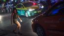 Foto pada 11 Oktober 2018 menunjukkan seorang wanita menyebrang jalan di Nana Red Light Distrik, Bangkok, Thailand. Nana Red Light District memang dikenal sebagai kawasan hiburan malam terbesar di Bangkok. (Romeo GACAD / AFP)