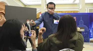 Perdana Menteri (PM) Thailand, Prayuth Chan-ocha menyemprot cairan disinfektan kepada barisan depan wartawan di ruang konferensi pers di Government House di Bangkok, Selasa (9/3/2021). Prayuth merasa terganggu saat wartawan mencecarnya dengan berbagai pertanyaan soal reshuffle kabinet. (AP Photo)