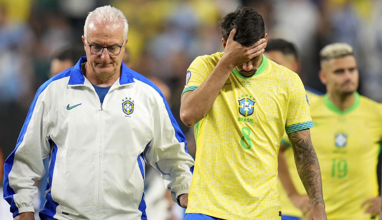 Pelatih Brasil, Dorival Junior  dan pemain Brasil, Marquinhos tertunduk setelah timnya disingkirkan Uruguay pada babak adu penalti saat laga perempat final Copa America 2024 di Allegiant Stadium, Las Vegas, Nevada, Minggu (07/07/2024) WIB. (AP Photo/Julio Cortez)