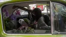 Roberta Machado dari Brasil menata bunga dan tanaman untuk dijual dengan Volkswagen Beetle 1969 yang diubah menjadi toko bunga keliling di Copacabana, Rio de Janeiro, Rabu (14/10/2020). Perempuan 51 tahun ini mengubah VW kodok untuk bertahan dari krisis akibat pandemi COVID-19. (MAURO PIMENTEL/AFP)